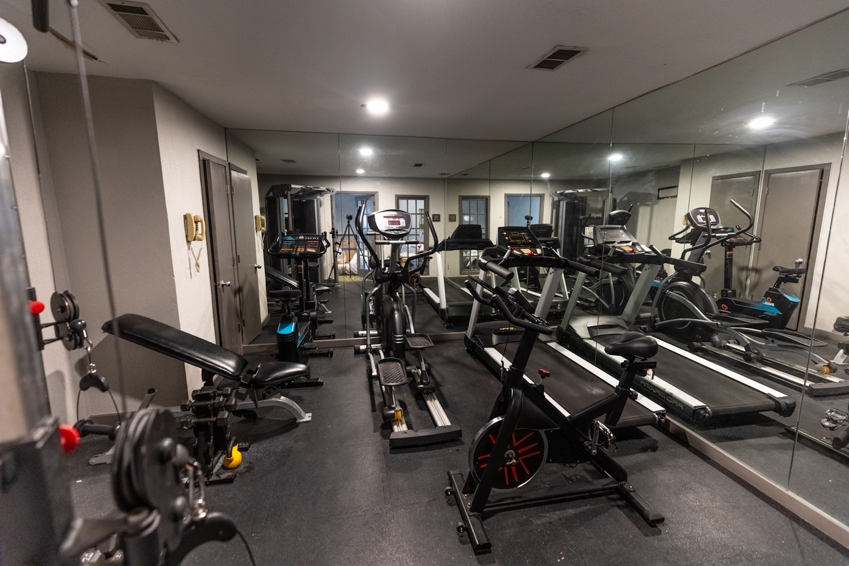 A gym with various exercise equipment, including treadmills, stationary bikes, and weight machines.