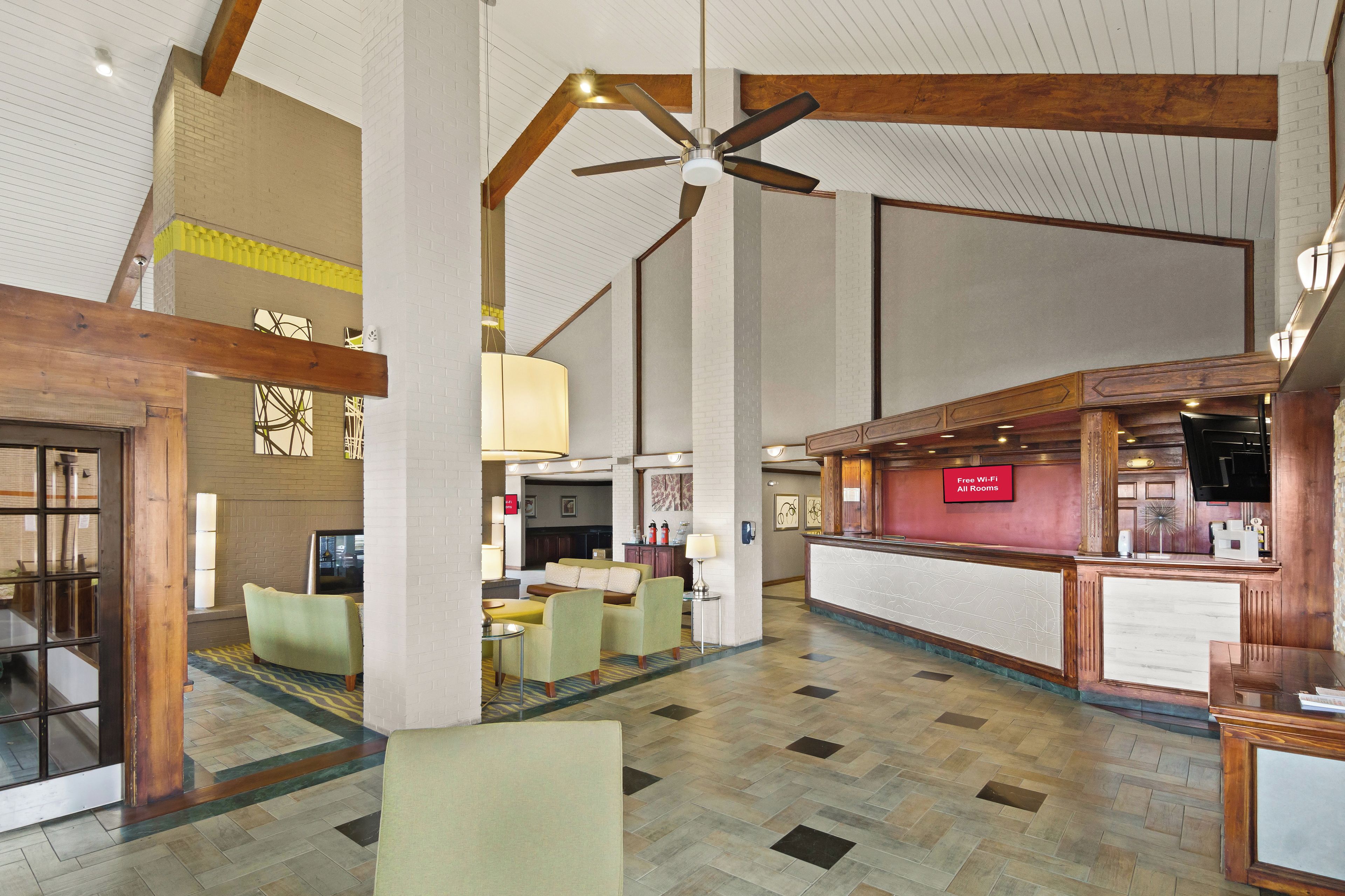 A spacious lobby with a high ceiling, a reception desk, and seating areas.