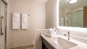 Un baño de hotel con un lavamanos grande, un espejo y dos toallas colgadas en la pared.