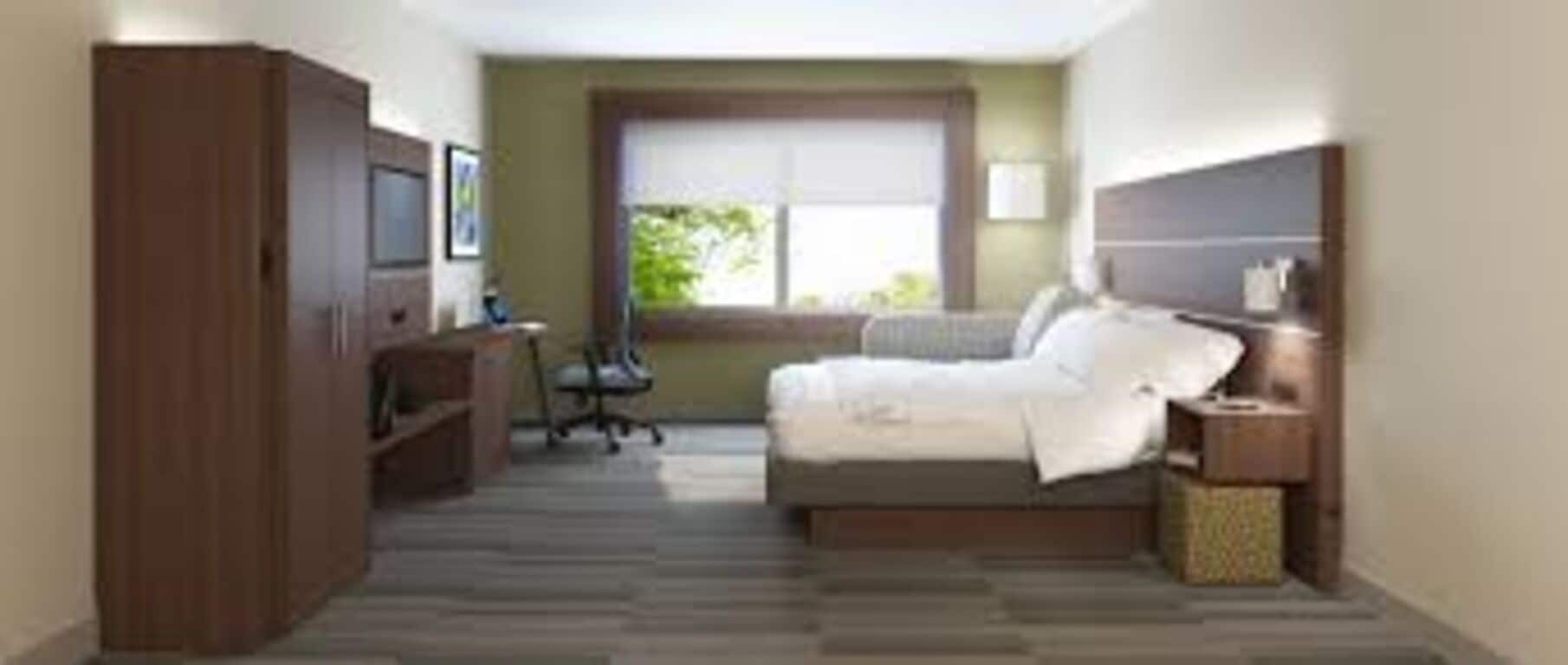 Ein Schlafzimmer mit Bett, Schreibtisch, Stuhl, Kleiderschrank und Fenster.
