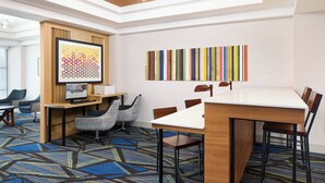 A modern meeting room with a large table, chairs, a computer, and a unique wall art piece.