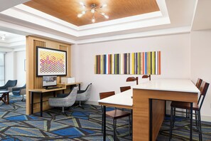 A modern meeting room with a large table, chairs, a computer, and a unique wall art piece.