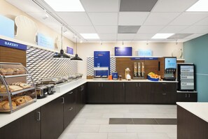 A breakfast area with a bakery section, a cereal and fruit display, and a refrigerator with yogurt, eggs, and milk.
