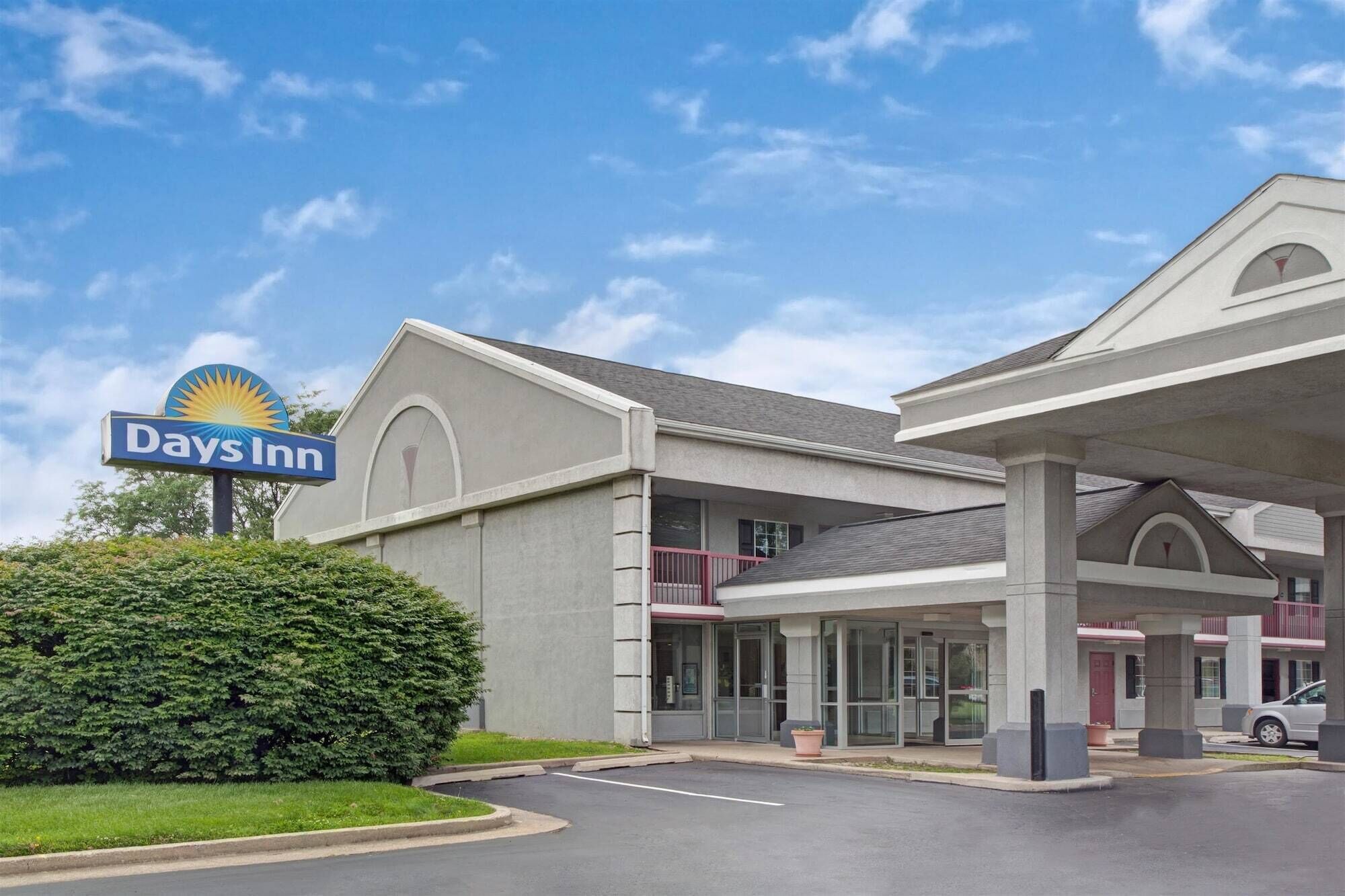 Un hotel Days Inn con cielo despejado, estacionamiento y césped bien cuidado.