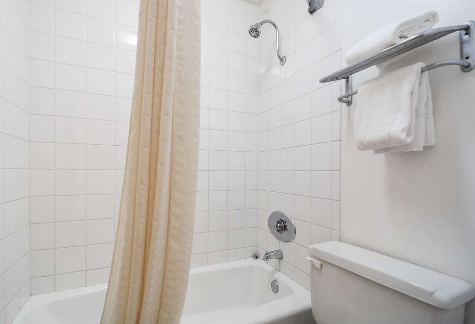 Et badeværelse med badekar, toilet og håndklædetørrestativ.