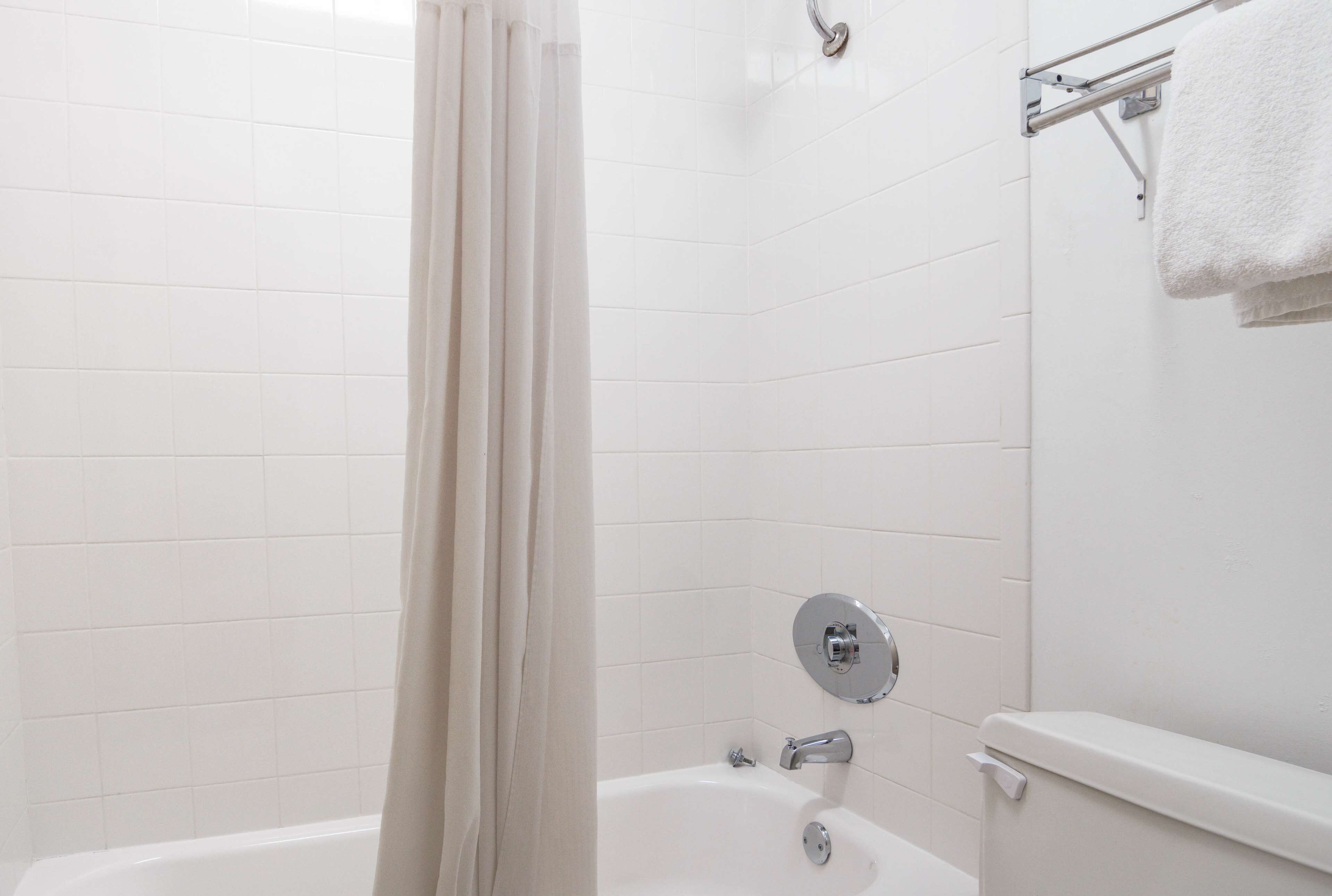 A bathroom with a bathtub, a shower curtain, and a towel rack.
