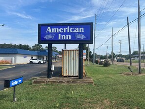 Une enseigne indiquant un hôtel américain, avec une flèche directionnelle.