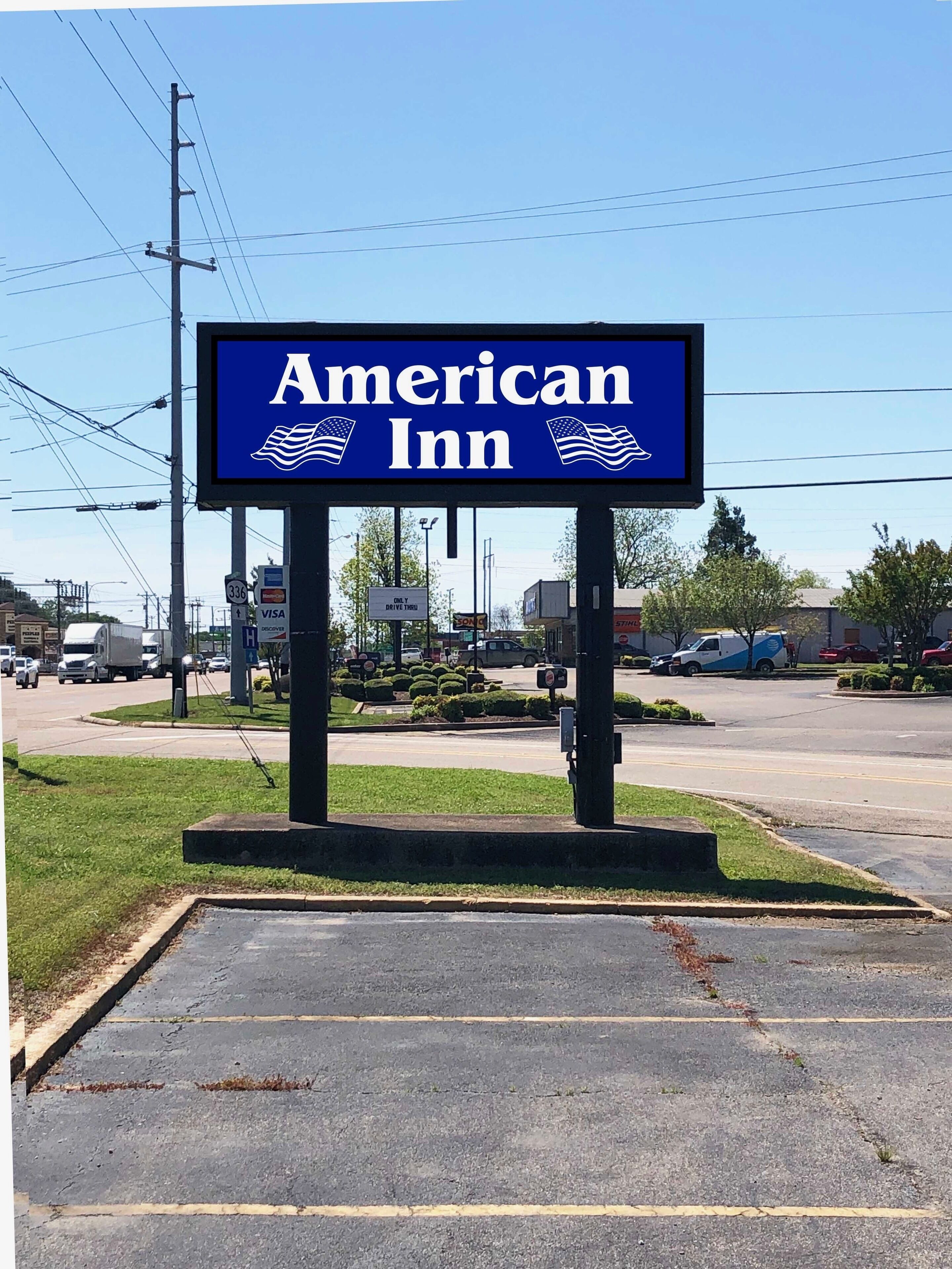 A sign for American Inn with a clear view of the parking lot and surrounding area.