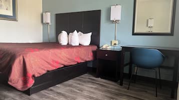 Una habitación de hotel con cama, escritorio, silla y un espejo grande.