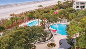 Un complexe hôtelier doté d’une piscine, offrant une vue sur la plage et comprenant plusieurs bâtiments.