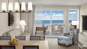 Une chambre d’hôtel avec un balcon, un coin repas et un espace salon offrant une vue sur l’océan.