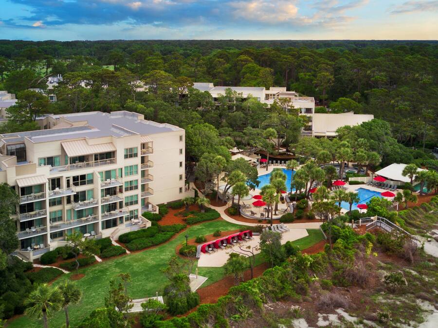 Vista aerea di un resort con diversi edifici, una piscina e aree verdi curate.