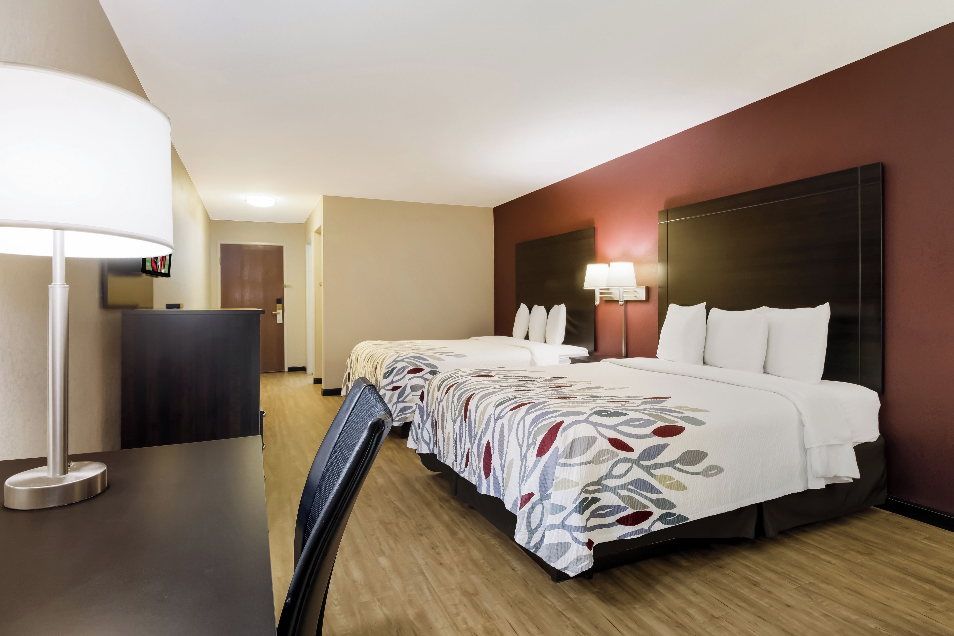 A hotel room with a bed, bedside tables, a desk, and a chair.