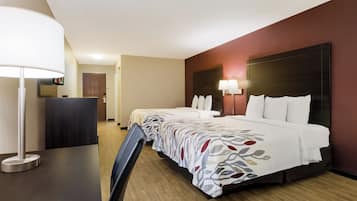 A hotel room with a bed, bedside tables, a desk, and a chair.