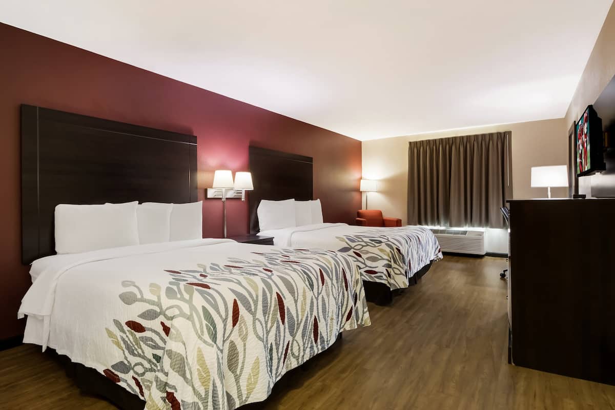 Habitación de hotel con dos camas, un escritorio y una televisión.