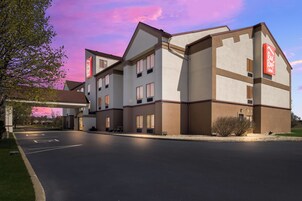 Un hotel de varios pisos con techo plano y un estacionamiento al frente.