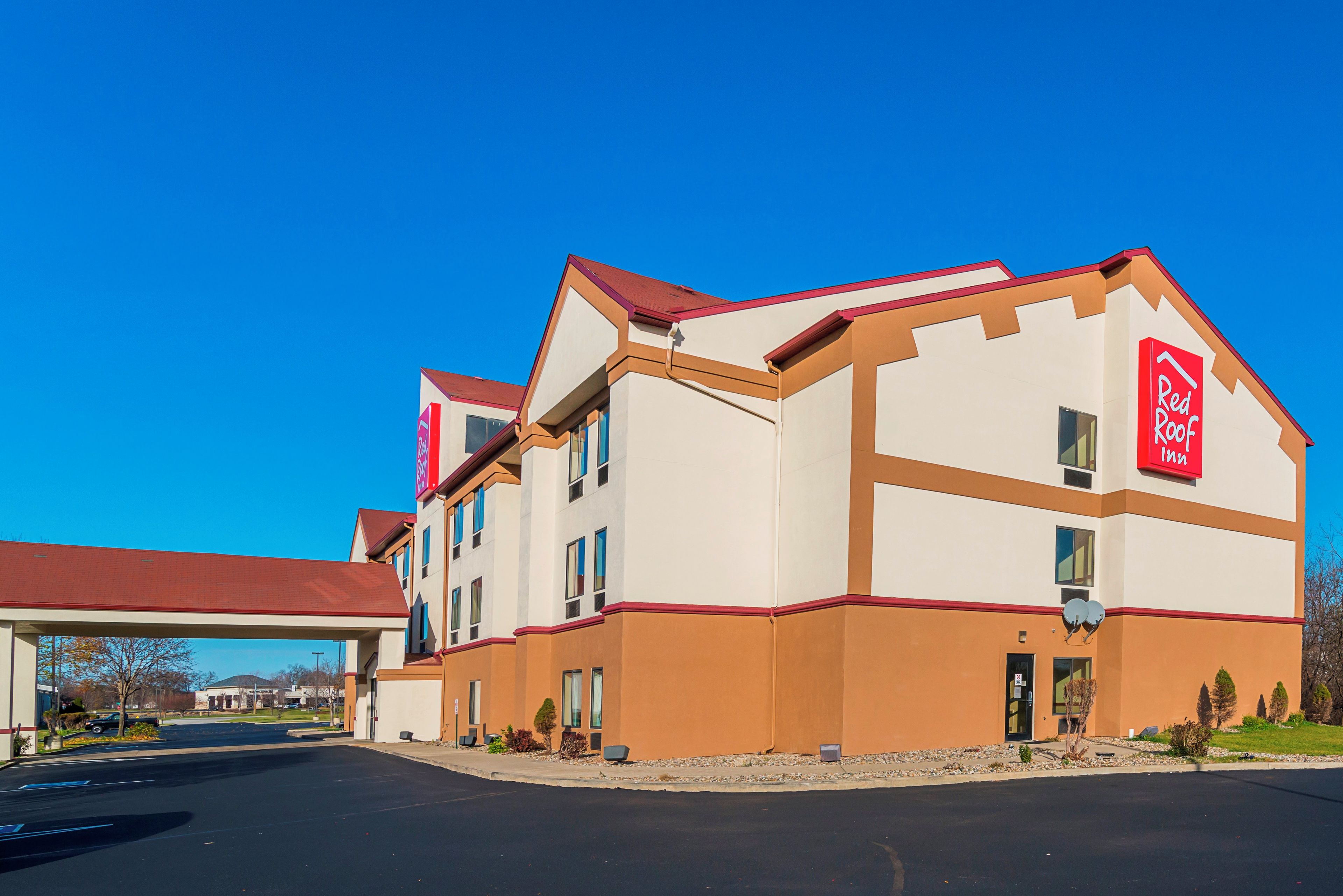 A Red Roof Inn with a two-story building, a parking lot, and a clear blue sky.