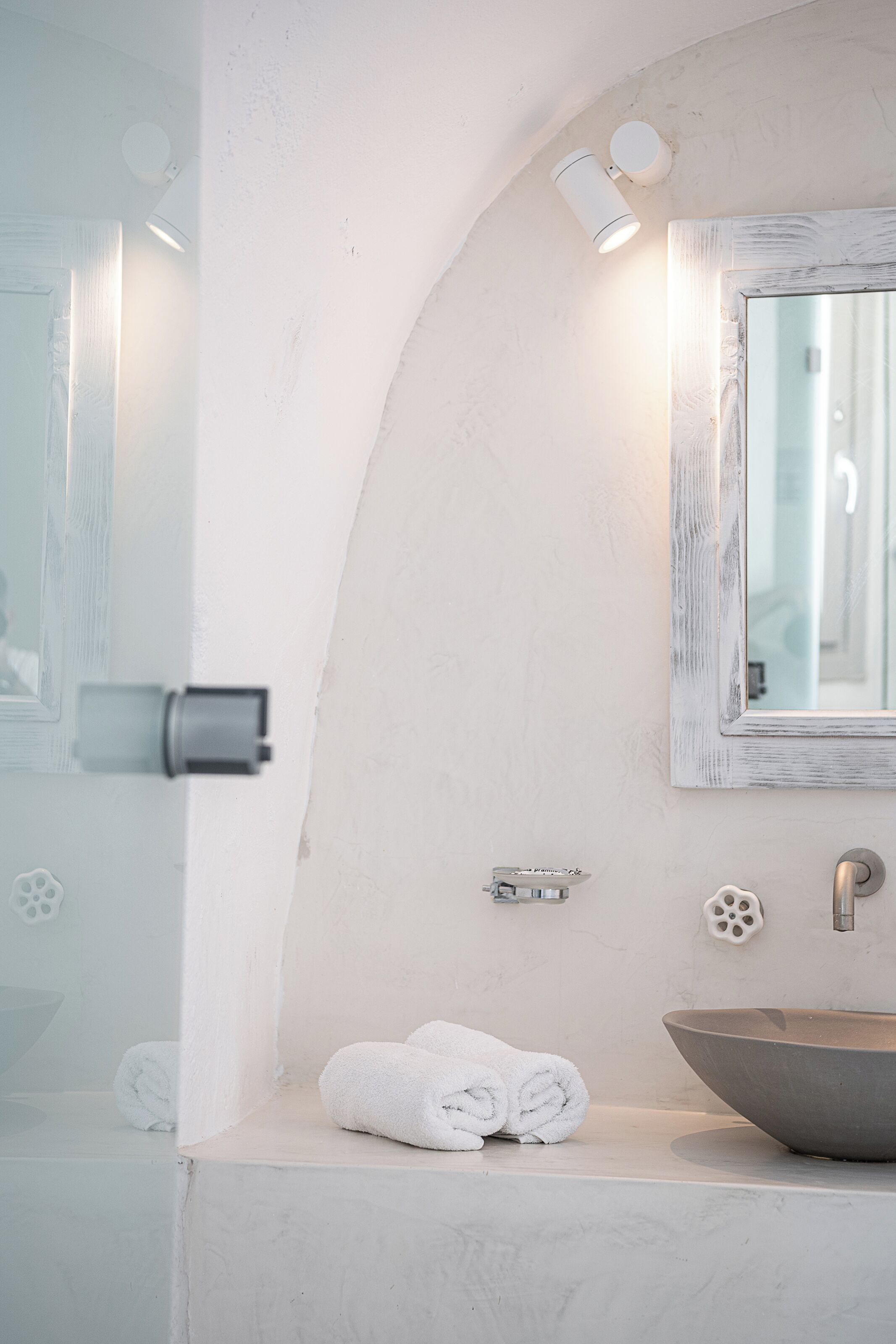 Un baño con lavamanos blanco, un espejo y un perchero para toallas.