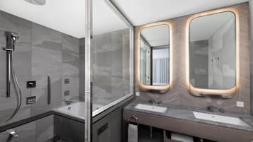 A modern bathroom with a glass-enclosed shower, two sinks, and a large mirror with illuminated frames.