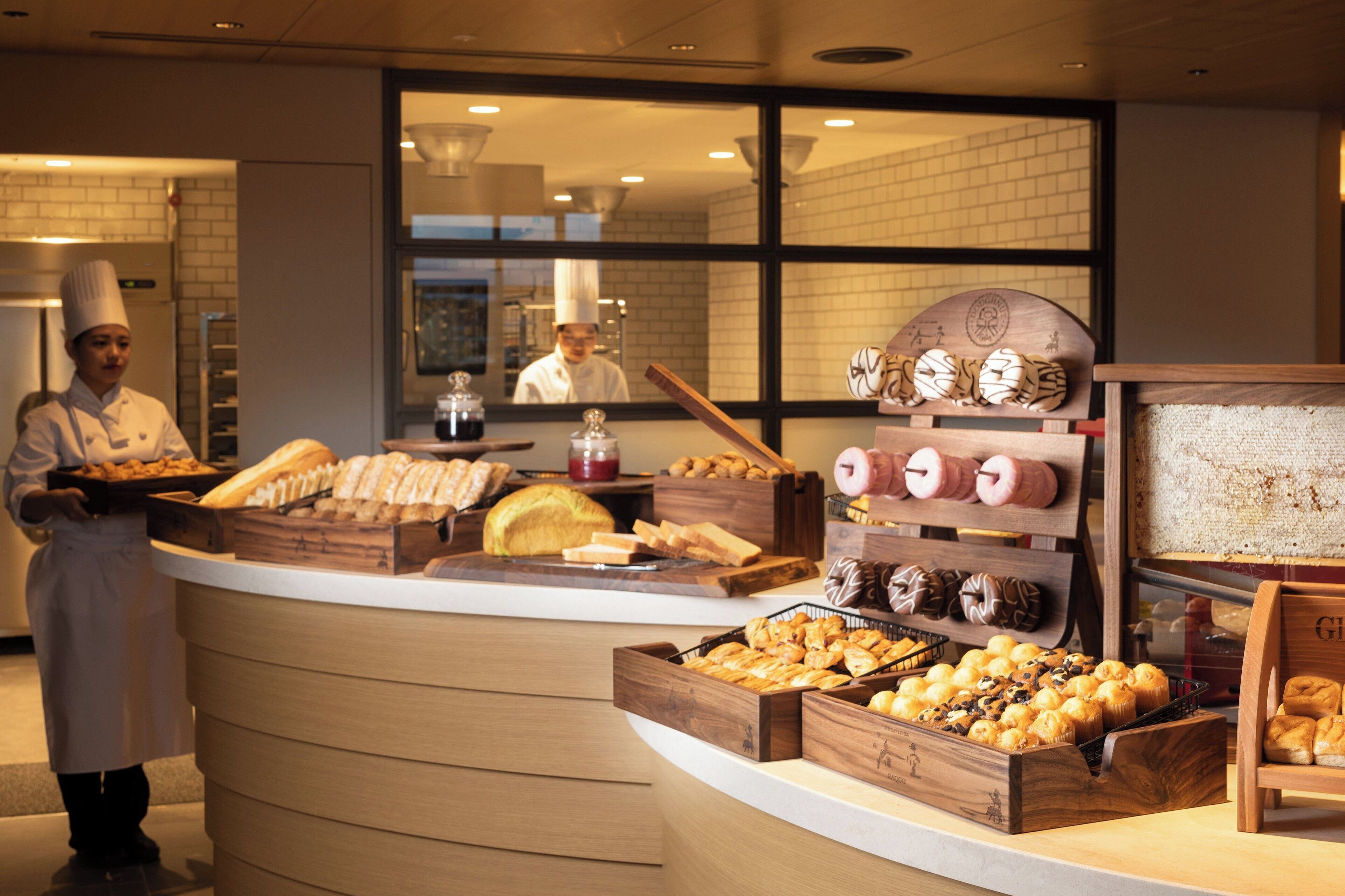 A bakery display with various baked goods and a chef in uniform.