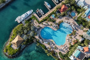An aerial view of a resort with a large heart-shaped pool, multiple boats docked, and a variety of buildings and amenities.