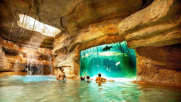 Formación rocosa natural con una piscina de agua cristalina y una zona de observación.
