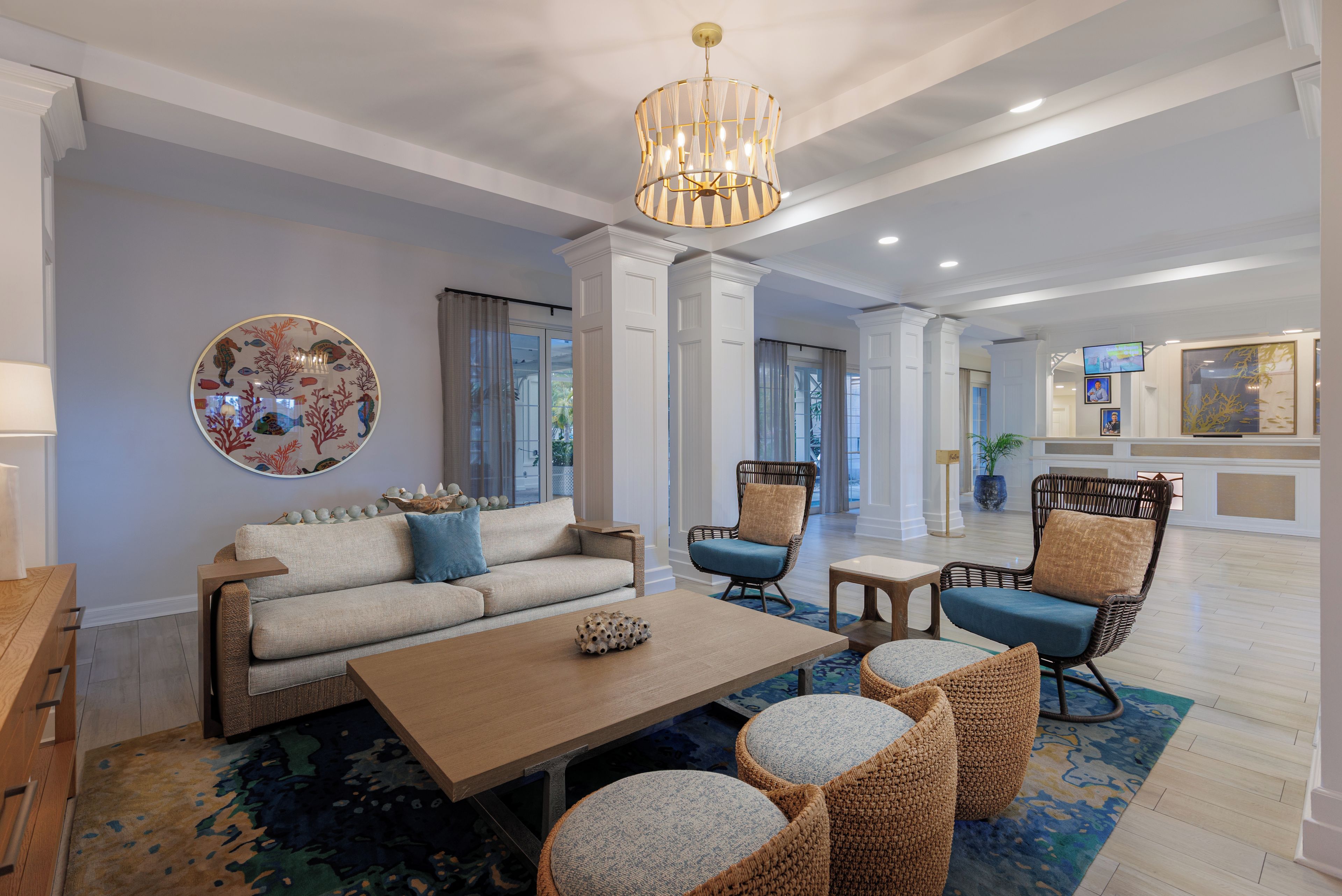 A modern living room with a sofa, coffee table, wicker chairs, and a decorative wall piece.