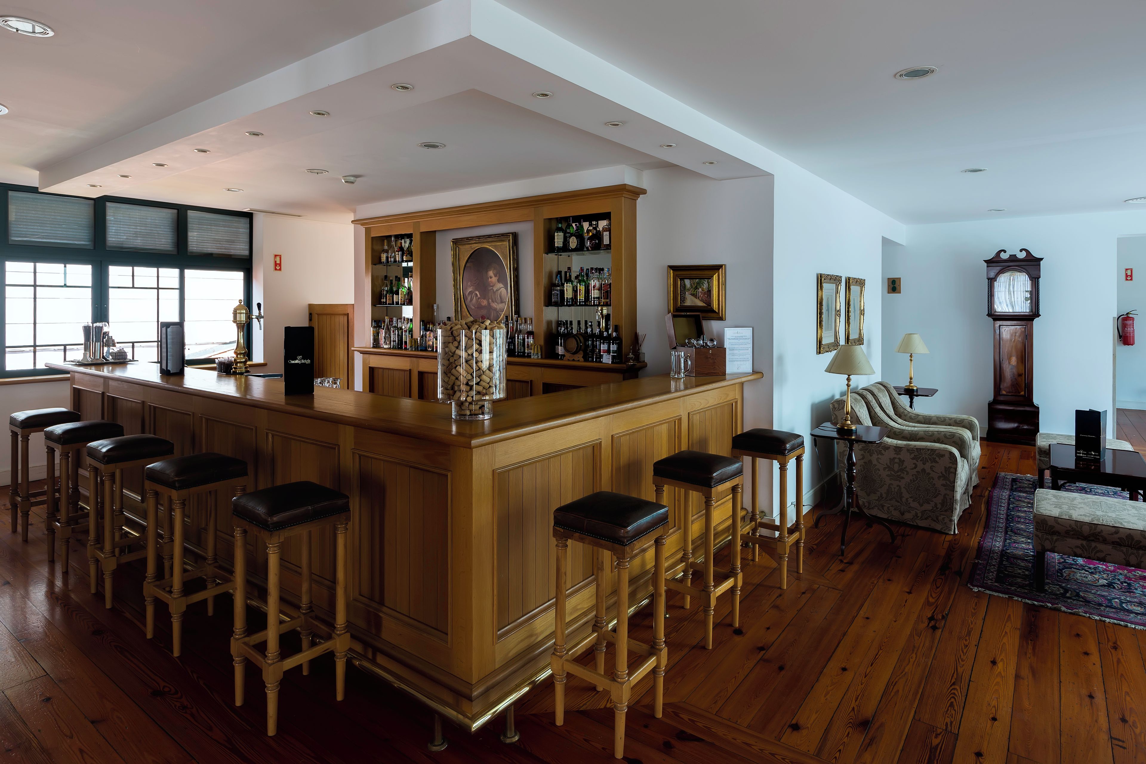 A bar area with wooden stools, a bar counter, and a wine bottle holder.