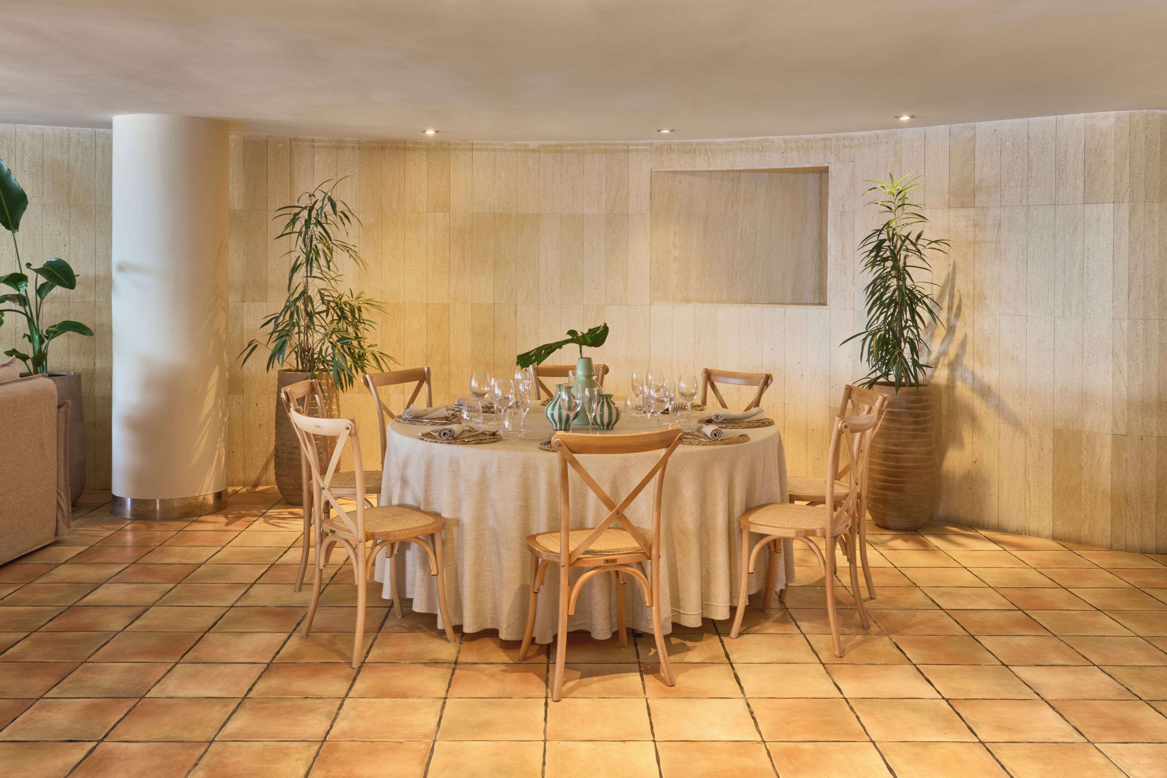 Un comedor con una mesa redonda dispuesta para cuatro personas, rodeada de sillas de madera.