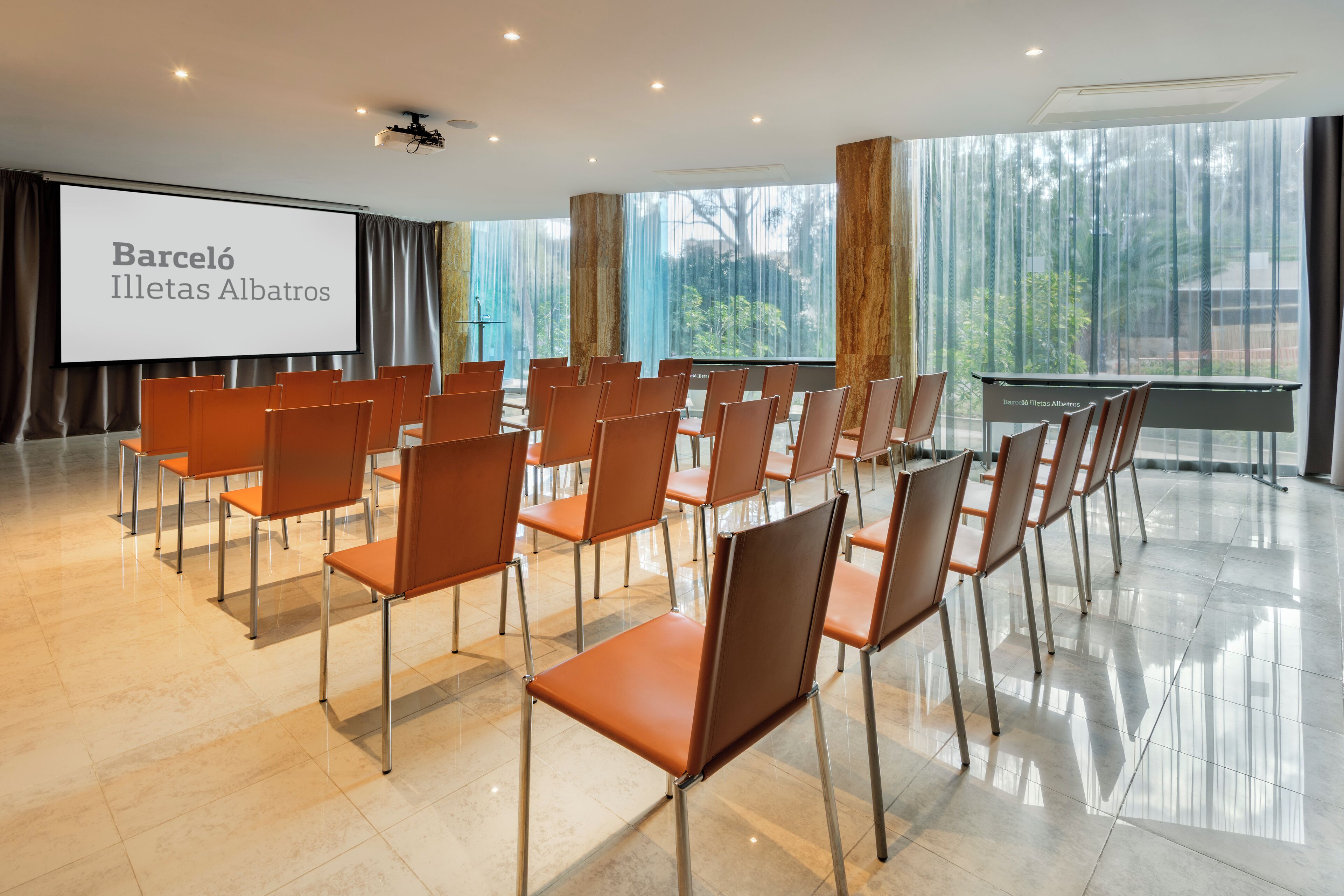 A conference room with rows of chairs facing a projection screen displaying "Barceló Illetas Albatros".