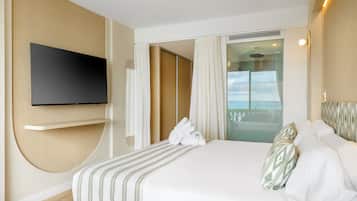 A hotel room with a large bed, a flat-screen TV mounted on the wall, a balcony with a view, and a sliding door leading to the balcony.