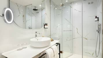 A modern bathroom with a white marble sink, a glass-enclosed shower, and a large mirror.