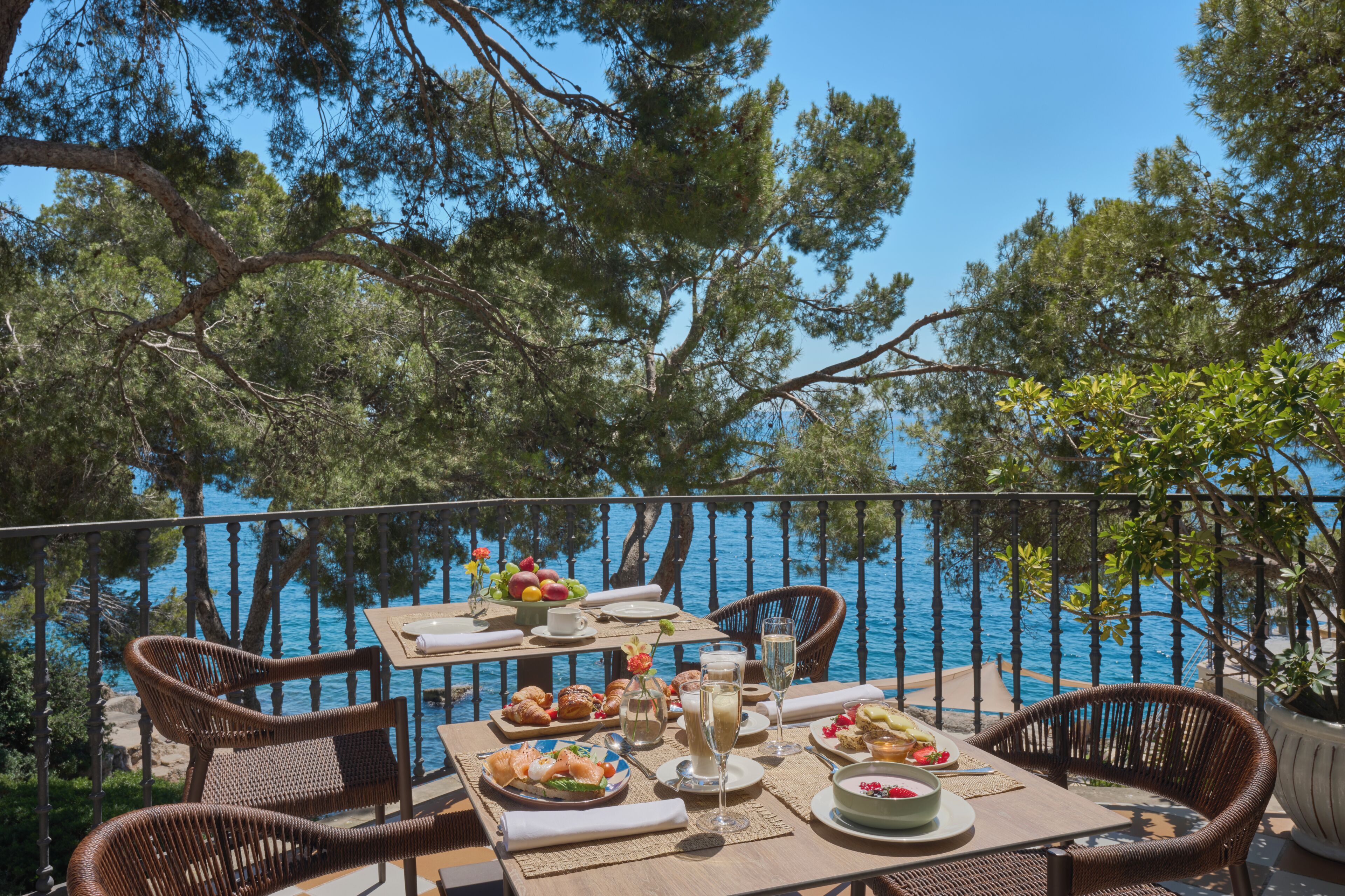 Un espacio de comedor al aire libre con una mesa para dos, con vista a un cuerpo de agua.