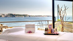 A balcony with a view of the sea and a cityscape, featuring a bed with towels and toiletries. - Barceló Illetas Albatros - Adults Only (Calvia)