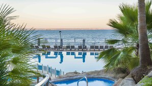 An infinity pool with a view of the ocean, surrounded by palm trees and lounge chairs. - Barceló Illetas Albatros - Adults Only (Calvia)
