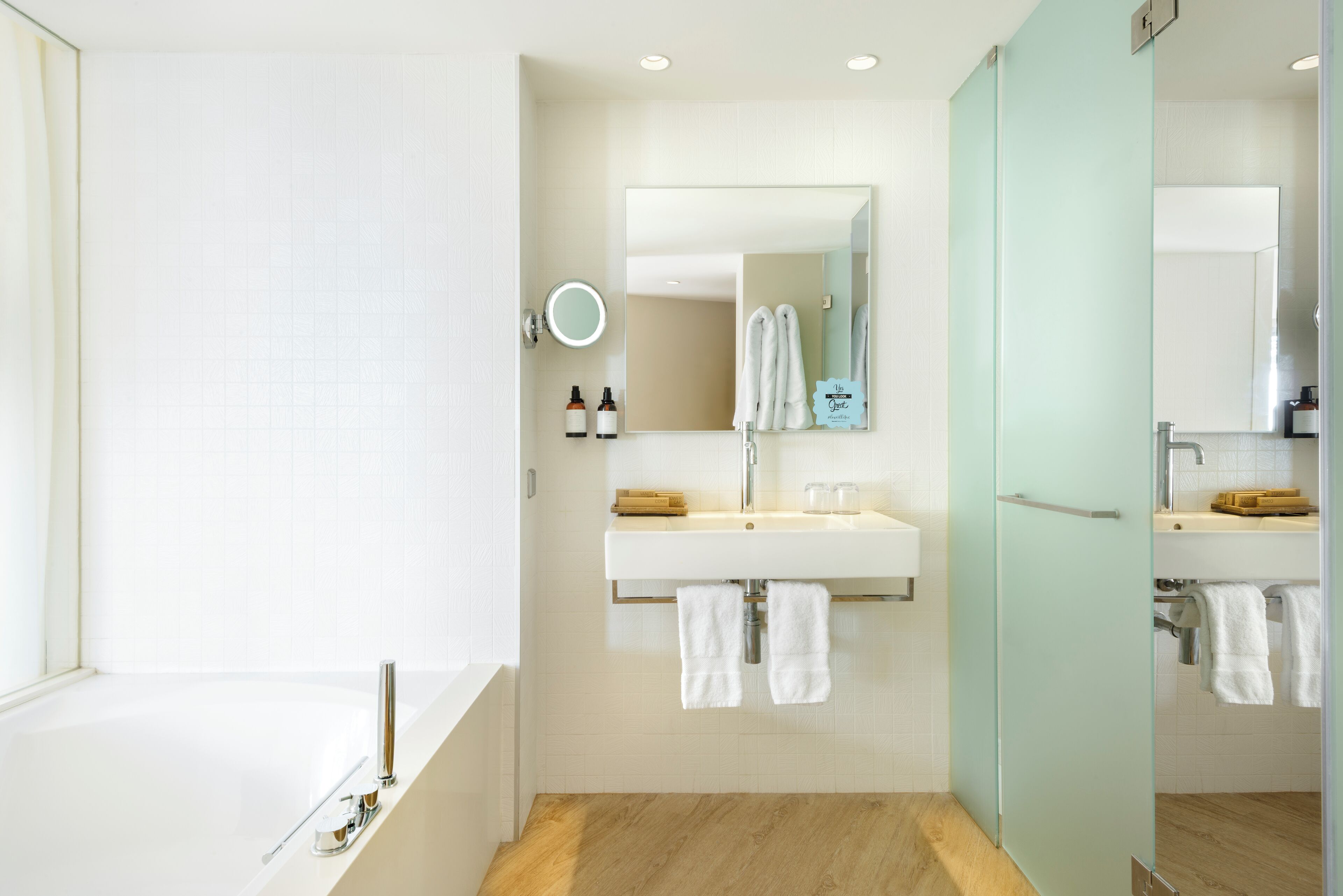 A modern bathroom with a bathtub, a sink with a mirror, and a glass shower enclosure.