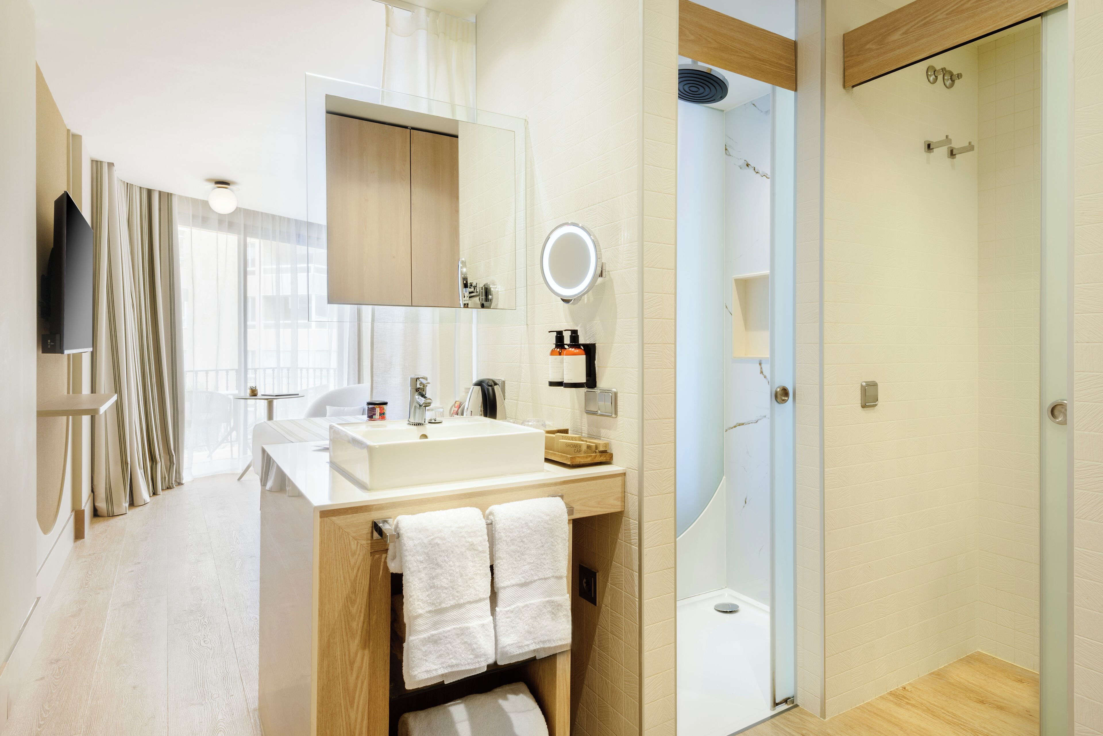 A modern bathroom with a large mirror, a sink, and a shower area.