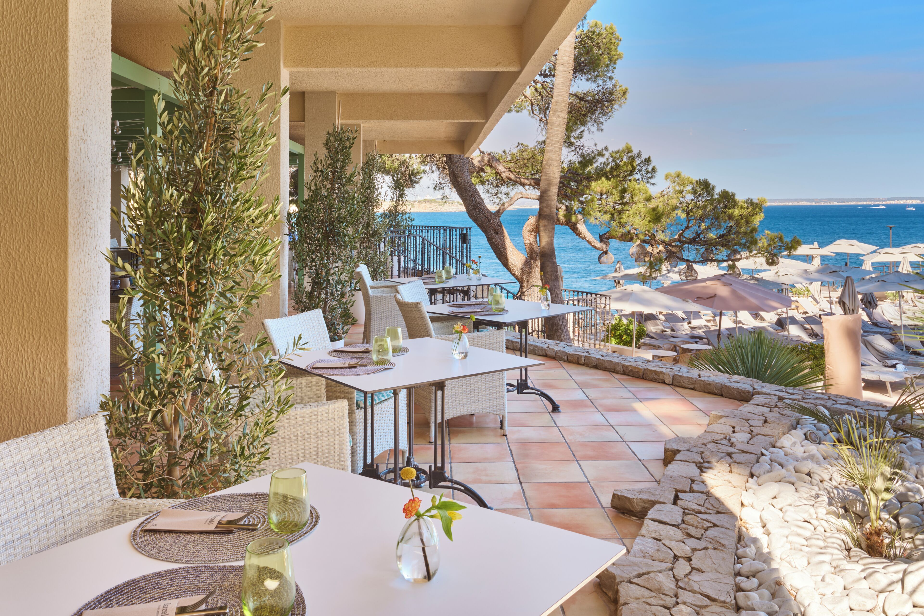 A terrace with outdoor seating, a view of the sea, and a stone pathway.
