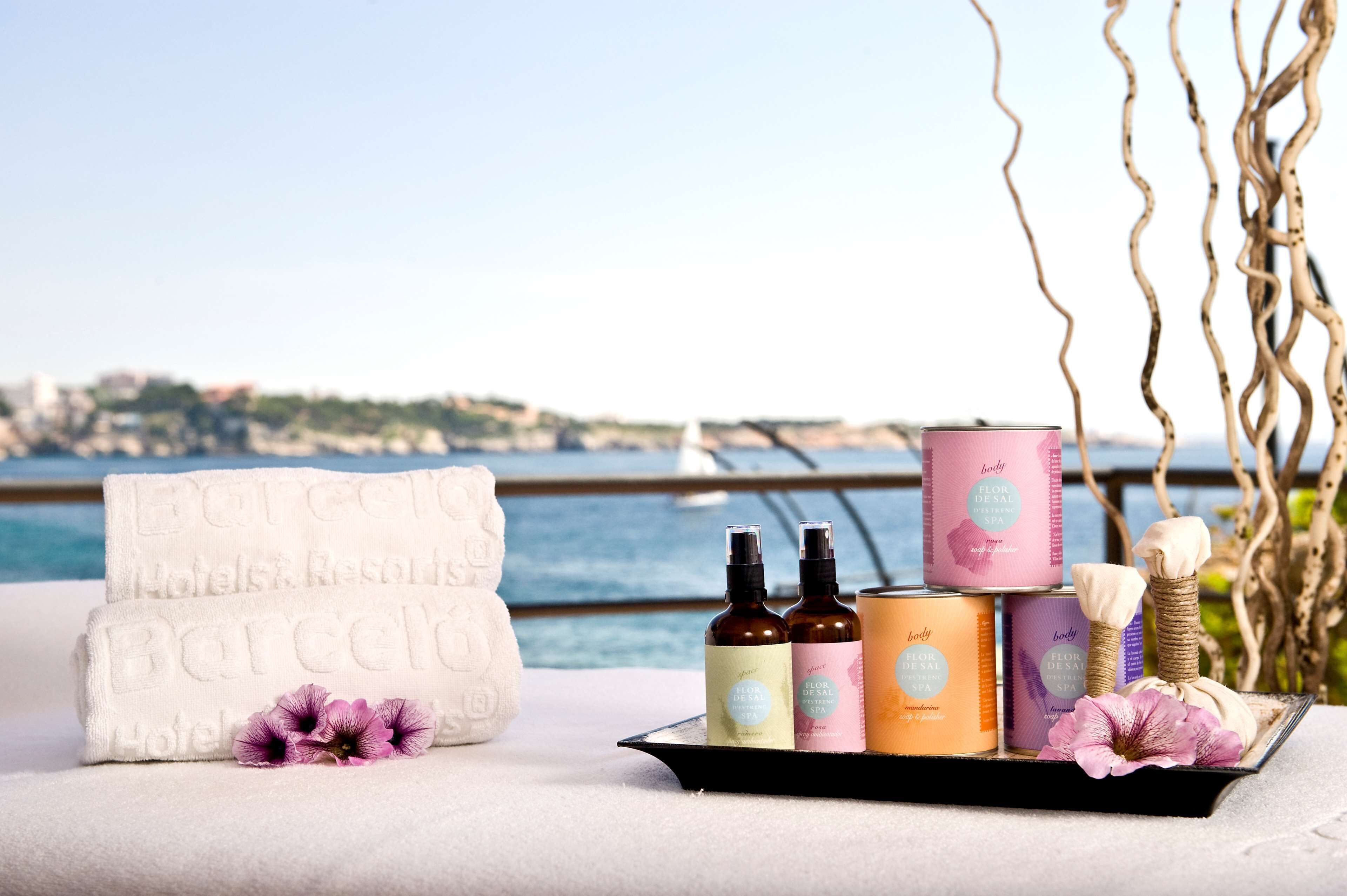 A tray with hotel towels, bath products, and a flower.