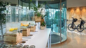A modern hotel lobby with a glass wall offering a view of the street, a reception desk, and a bike rack. - Barceló Illetas Albatros - Adults Only (Calvia)
