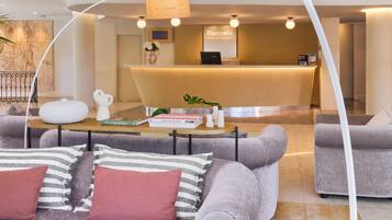 Un hall d’hôtel moderne avec un comptoir d’accueil, des canapés et une table basse avec des livres.