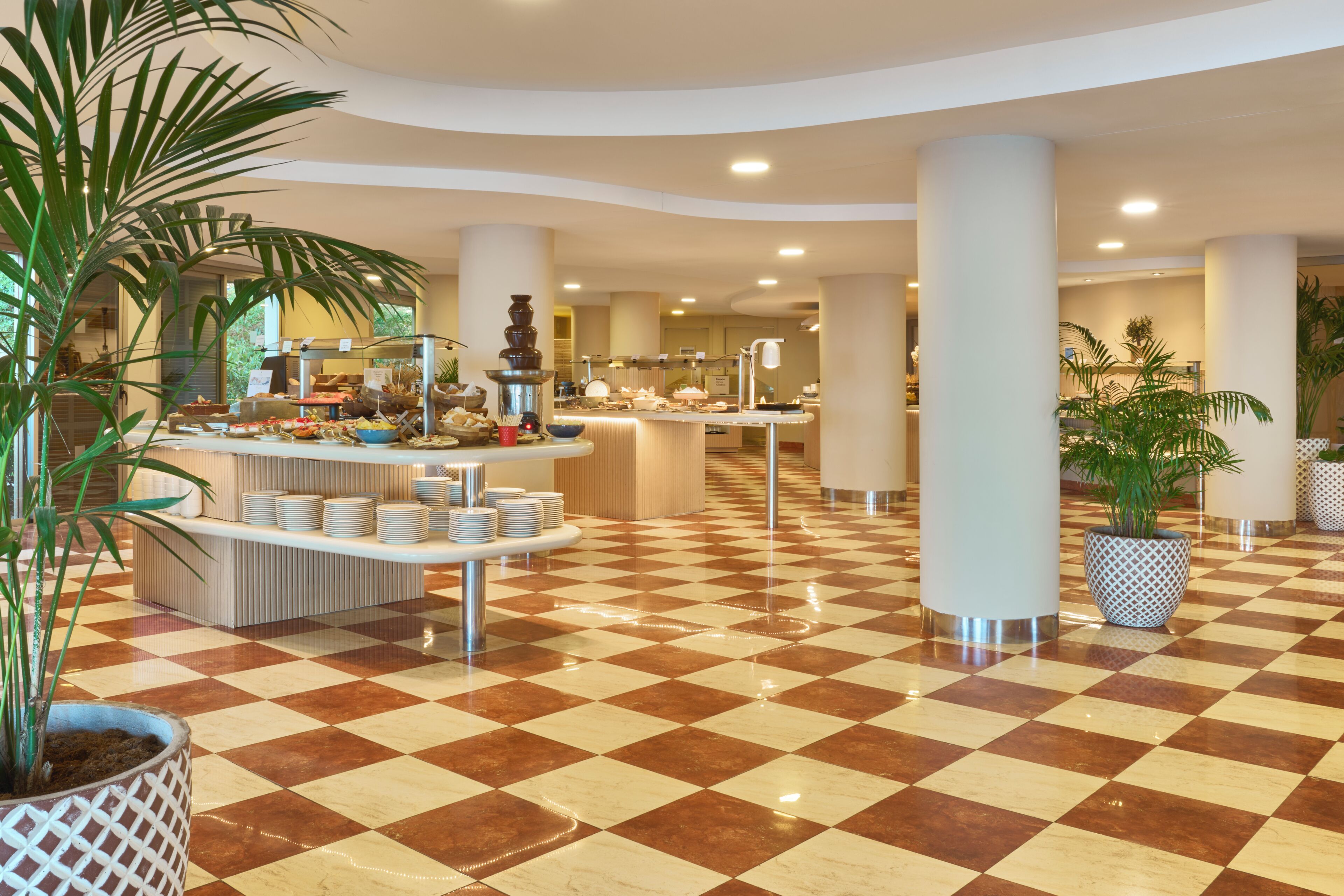 A hotel lobby with a checkered floor, buffet area, and large pillars.