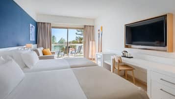 A hotel room with two beds, a desk, a TV, and a balcony with outdoor seating.