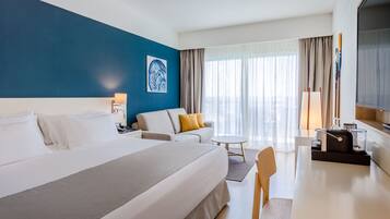 Una habitación de hotel con una cama grande, un sofá, un escritorio y un televisor.