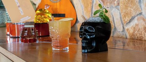 A bar area with a guitar, drinks, and a skull-shaped cocktail glass.