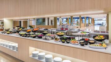 A buffet with various food items and stacked white plates.