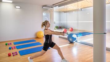 Un gimnasio con colchonetas de ejercicio, una pelota grande de gimnasia y un saco de boxeo.