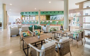 A modern lounge area with wicker furniture, a bar with stools, and a green accent wall.
