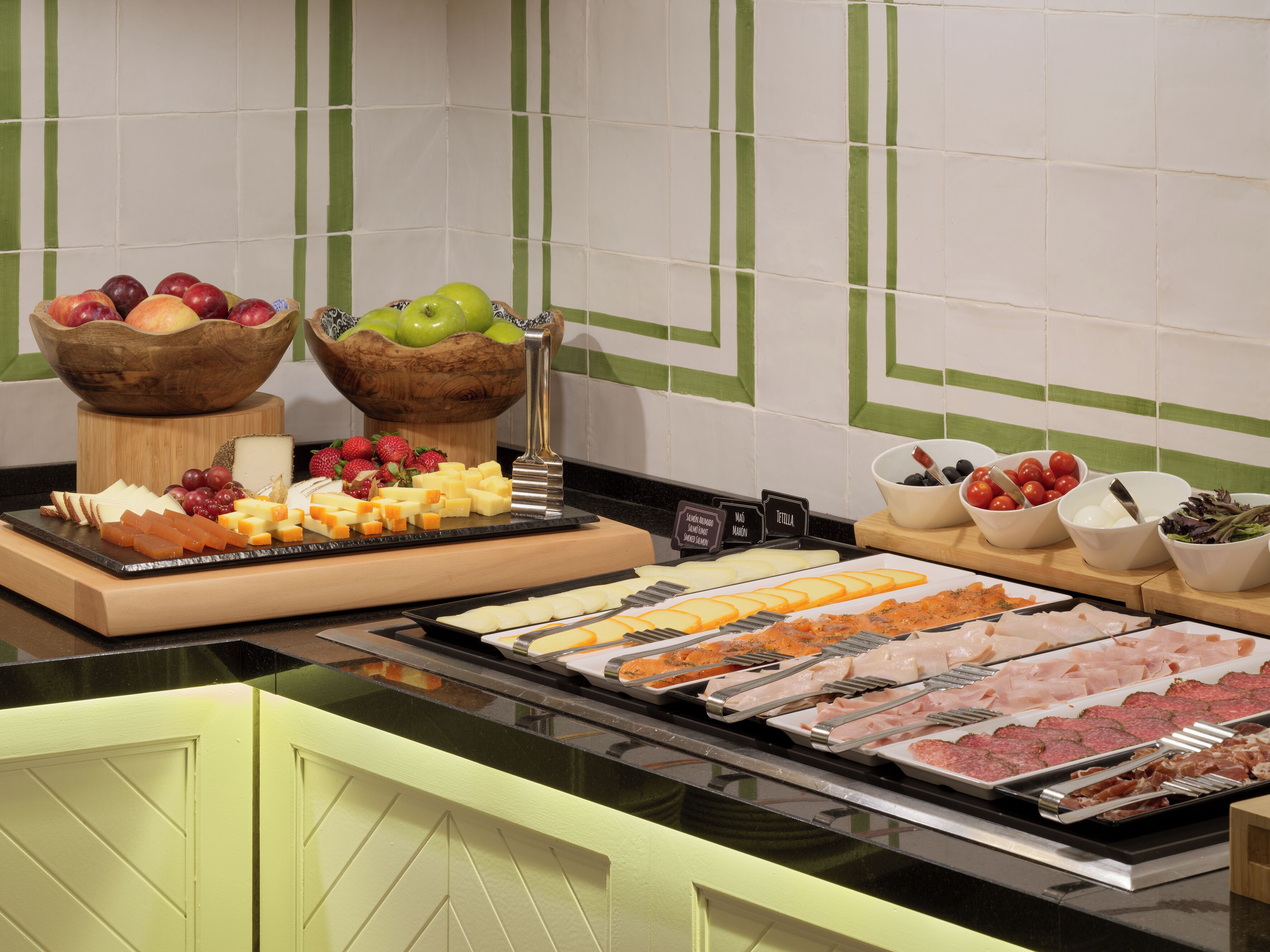 Un bufé con distintos alimentos, como frutas, quesos y carnes.