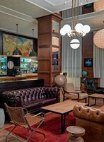 Una zona de bar con un sofá de cuero, sillas de madera y un globo terráqueo.